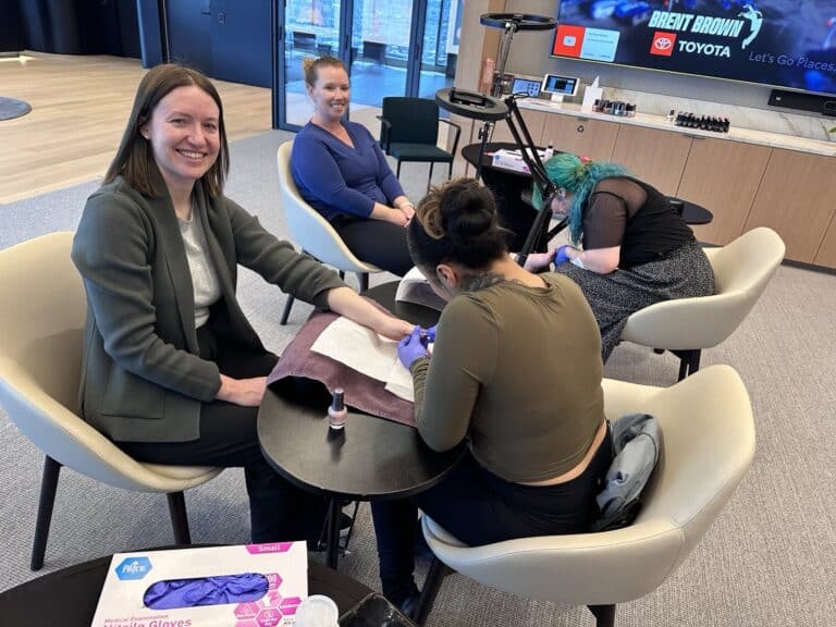 two wonderful employees receiving a manicure and a pedicure service in their office.