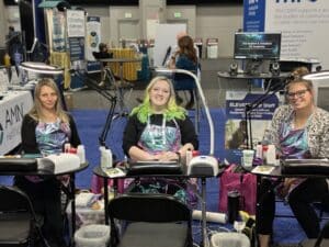 Three nail techs offering onsite custom nail services for AMN at their tradeshow